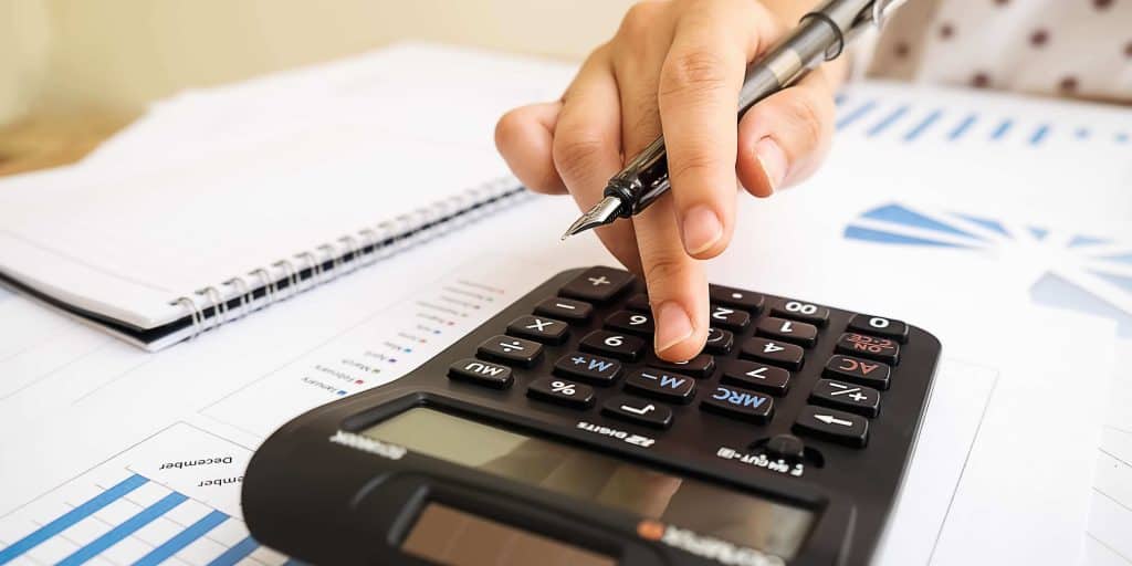 oseba uporablja kalkulator za izračun stroškov in plač
